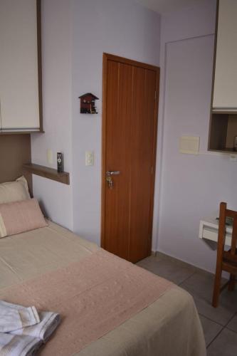 sypialnia z łóżkiem i drewnianymi drzwiami w obiekcie Aconchego My Place w mieście São João del Rei