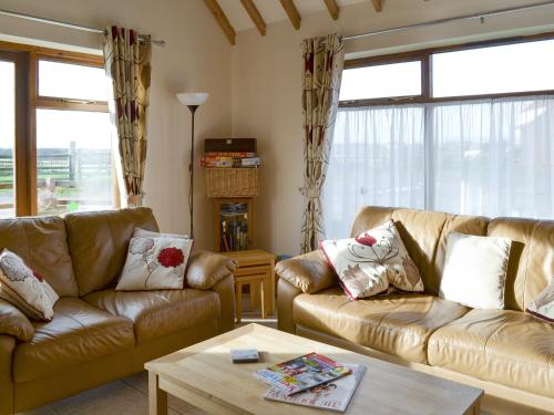 a living room with two leather couches and a table at Kingfisher Cottage - 25114 in Flamborough