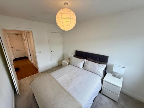 a bedroom with a white bed and a lamp at Cosy apartment near Edinburgh city centre in Edinburgh
