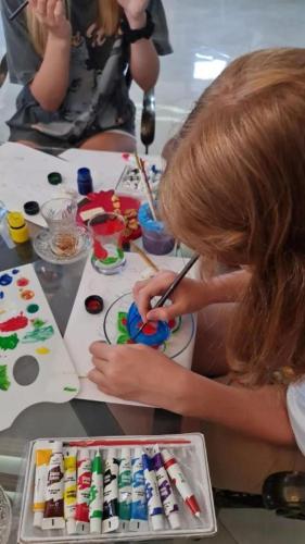 a young girl painting a cake with a paintbrush at NovART Gallery & Sea Hotel in Sumqayyt
