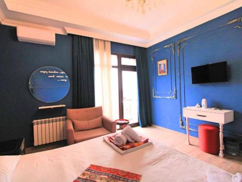 a bedroom with blue walls and a bed and a chair at NovART Gallery & Sea Hotel in Sumqayyt