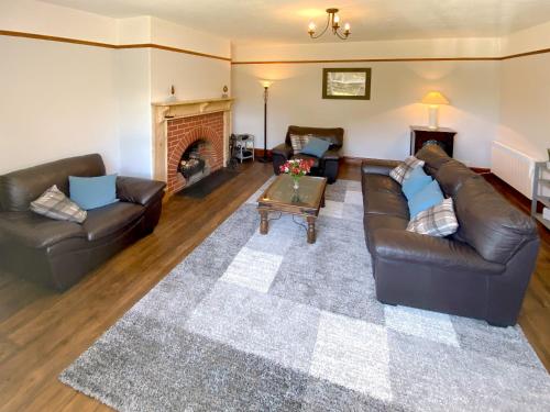a living room with two leather couches and a fireplace at Penfound Country Cottage in Poundstock
