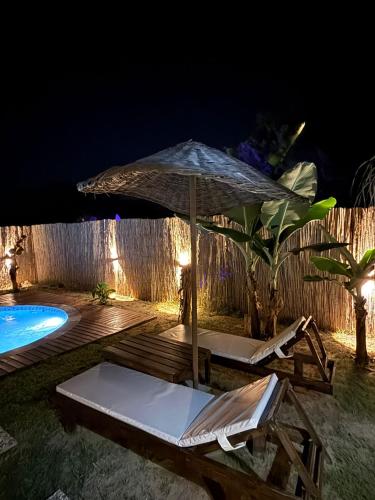 an umbrella and chairs next to a pool at night at Kiriş Garden Hotel in Kemer