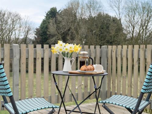 a table with a vase of flowers on it next to two chairs at Meadow View in Swafield