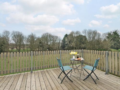 a table and chairs on a deck with a fence at Meadow View in Swafield
