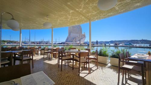 a restaurant with tables and chairs and a view of the harbour at Lisbon Belém Chalenger in Lisbon
