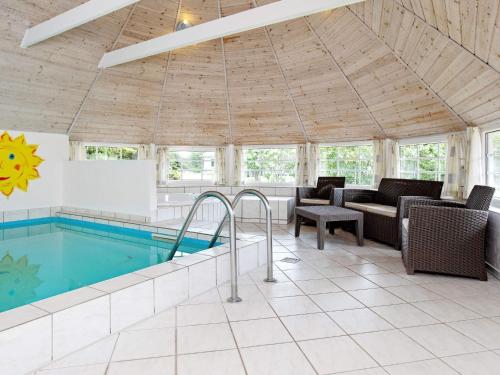 a swimming pool in a living room with a couch and chairs at 5 star holiday home in Væggerløse in Bøtø By