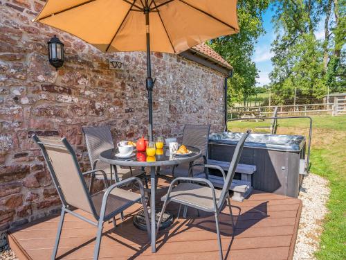 a table and chairs with an umbrella on a deck at Court Park Barn in Chepstow