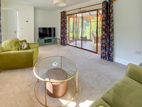 ein Wohnzimmer mit einem Glastisch und Stühlen in der Unterkunft Rose Cottage in Blakemere