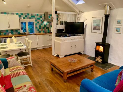 a living room with a couch a table and a stove at Chapel Barn in Bodmin