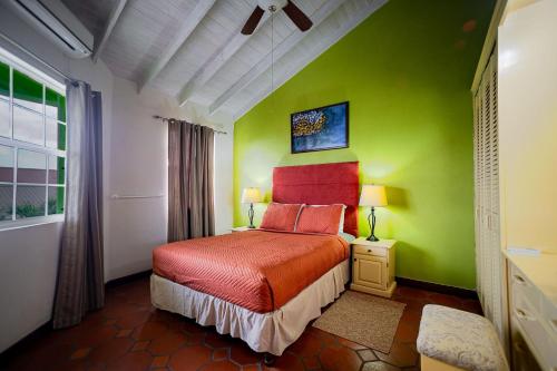 a bedroom with green walls and a bed with red pillows at Best E Villas Prospect St James in Saint James