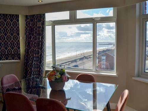 Un comedor con mesa y vista a la playa. en Crows Nest, en Bridlington