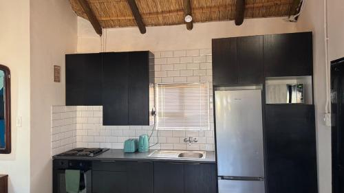 cocina con armarios negros, fregadero y nevera en 505 Loft, en Maseru