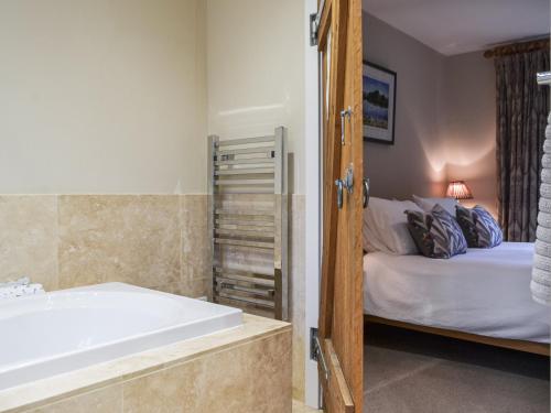a bathroom with a bath tub next to a bed at Over Brandelhow in Borrowdale Valley