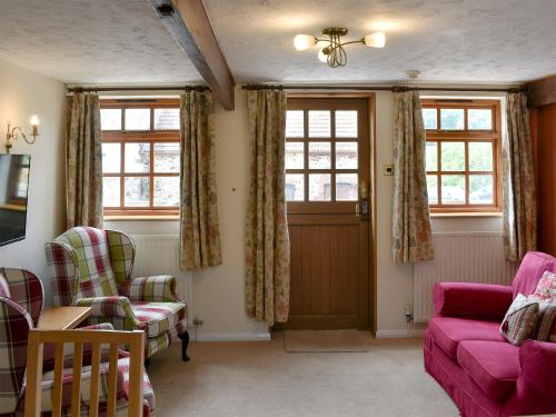 a living room with a pink couch and windows at The Milking Parlour in Sidbury