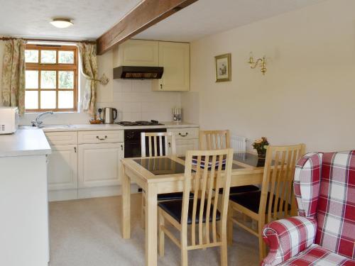 a kitchen with a wooden table and chairs and a table and a counter at The Milking Parlour in Sidbury