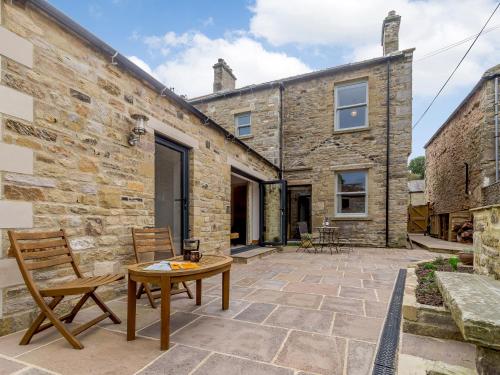 a patio with a table and chairs in front of a stone building at Temple House in West Burton