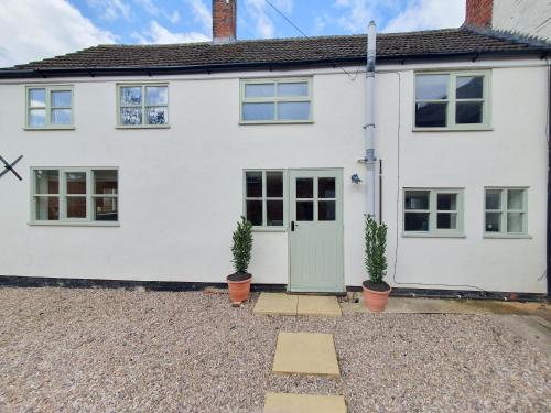 a white house with potted plants in front of it at Drapers Cottage in Foxton