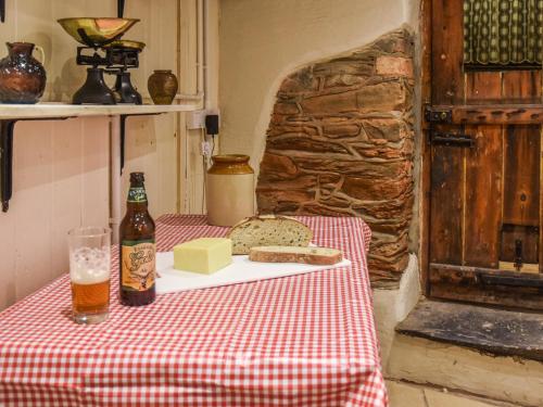 einen Tisch mit einer Flasche Bier, Brot und Käse in der Unterkunft Riverside Cottage in Lynton