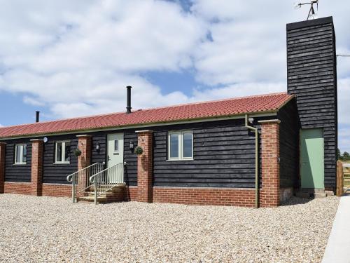 una casa indipendente con il tetto nero e rosso di Waxwing Cottage a Foxton