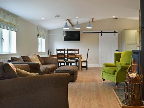 a living room with couches and a dining room at Waxwing Cottage in Foxton