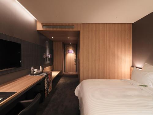 a hotel room with a bed and a television at Hotel Dùa in Kaohsiung
