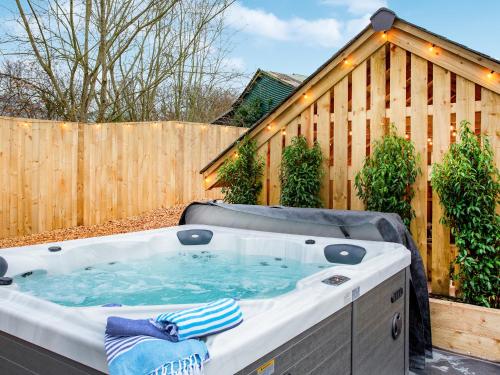 una bañera de hidromasaje en un patio trasero con una valla de madera en Eastacombe, en Atherington