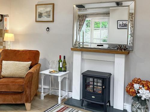 a living room with a fireplace and a chair and a mirror at The Farriers - 26967 in Windermere