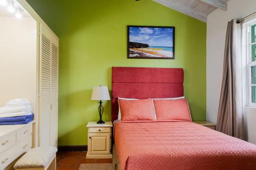 a bedroom with a red bed with a green wall at Best E Villas Prospect St James in Saint James