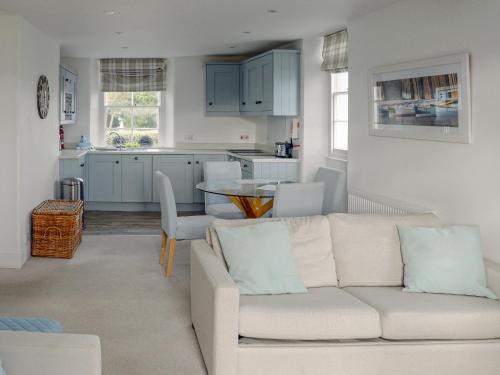 Una sala de estar con un sofá blanco y una cocina. en Charborough House Apt 3, en Salcombe
