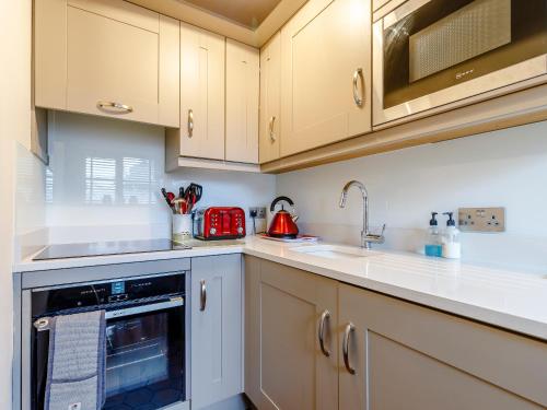 a kitchen with white cabinets and a dishwasher at The Pigsty - Uk30945 in Barthomley