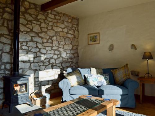 a living room with a blue couch and a stone wall at Barn End Cottage in Millers Dale