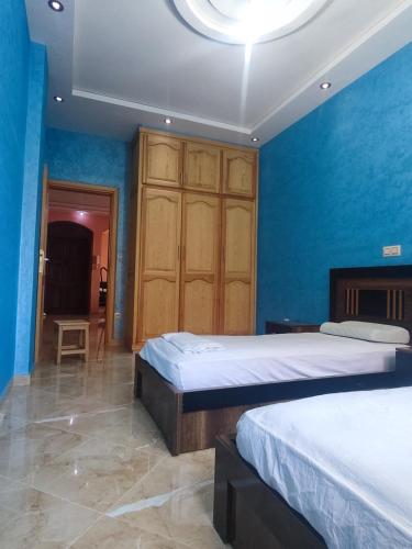 a bedroom with two beds and a blue wall at Appartement 3 chambres in Berkawe
