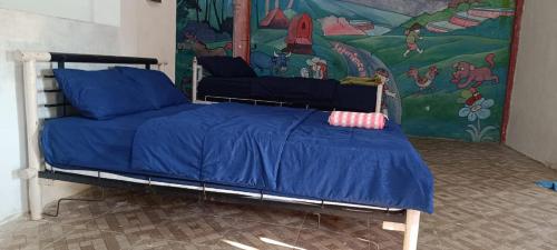 a bedroom with a bed with blue sheets and a mural at Tetebatu Terrace Hostel in Tetebatu