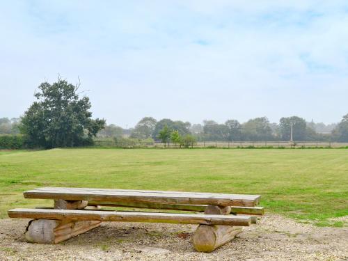 a wooden bench sitting in front of a field at Burfields Barn in Rickinghall