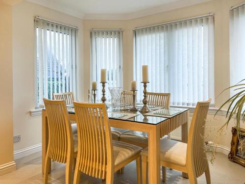 a dining room with a table and chairs and windows at Littlewood Gardens in Montrose