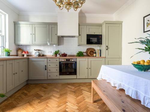 a kitchen with white cabinets and a table at Auchengool House in Kirkcudbright