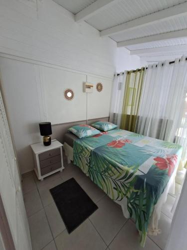 a small bedroom with a bed and a night stand at Charmant F2 créole in Sainte-Luce