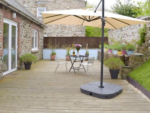 a patio with an umbrella and a table and chairs at Llwynbedw - 28464 in Cardigan