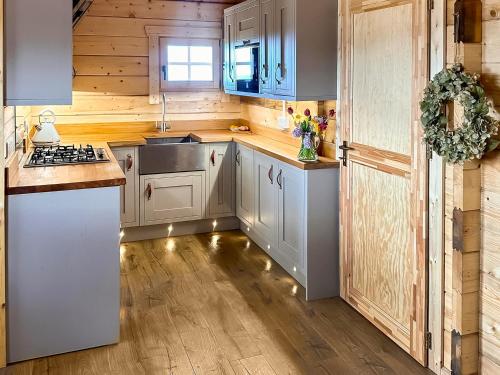 a kitchen with wooden walls and white cabinets at Wind Hall Log Cabin in Gosforth