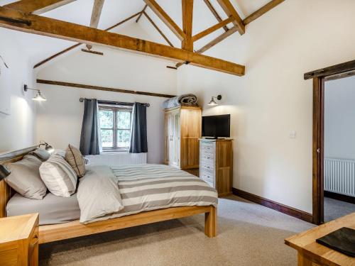 a bedroom with a large bed and a television at High House Barn - Uk36929 in Foulsham
