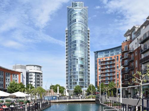 a tall glass building next to a river with buildings at No1 The Two Bedroom Balcony View in Portsmouth