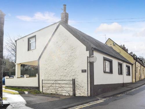 a white building with a gate on a street at Thistle Dee in Wooler