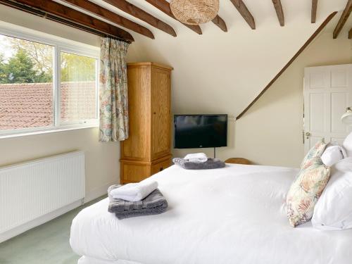 a bedroom with two beds and a tv in it at Linnets in Fitzhead