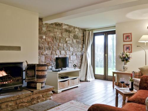 a living room with a fireplace and a stone wall at Bramble Cottage in Newland