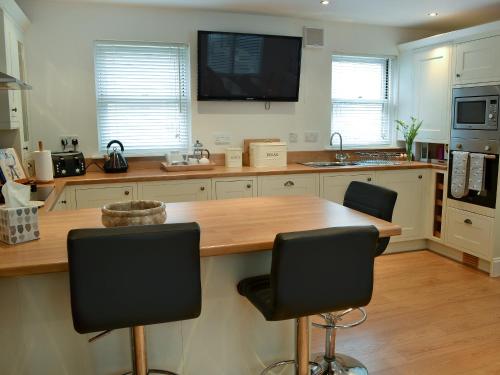 a kitchen with a wooden counter and two bar stools at The Old Forge in Alnwick