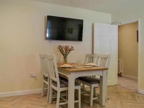 a dining room table with chairs and a television on the wall at Holly - Apartment in Aberfoyle