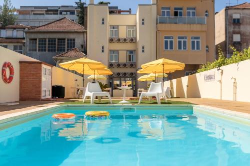 a swimming pool with chairs and umbrellas on a building at 731 Costa Cabral Metro Residence in Porto