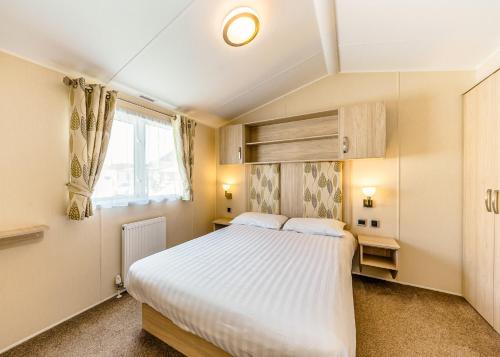 a small bedroom with a white bed and a window at Riverside Holiday Village in Uphill