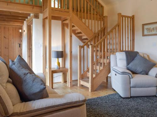 ein Wohnzimmer mit 2 Stühlen und einer Treppe in der Unterkunft Hayloft Cottage in Ludchurch